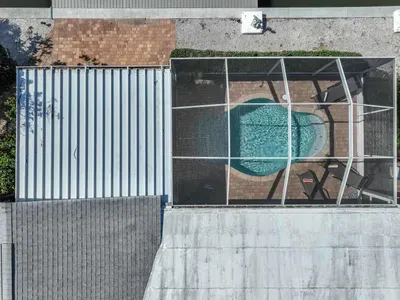 Take in the breathtaking top view of the property, where you can spot the sparkling pool through the lanai screen. This picturesque perspective showcases the perfect blend of outdoor relaxation and tropical beauty, offering an ideal retreat for you.