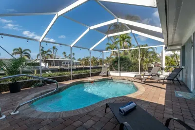 This sparkling  pool is surrounded by comfy lounge chairs, tropical landscaping, and tranquil canal views all framed by a spacious lanai. Whether you're sipping morning coffee poolside or enjoying an evening swim under the string lights.