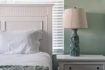 This queen-sized bed is complemented by two side tables and matching lamps, creating a functional yet serene retreat. The ideal setup for comfort and convenience.