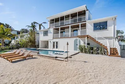 Beautiful three-story waterfront home featuring a pool, spa, and private sandy area with loungers. Multiple balconies offer stunning canal views—perfect for soaking up the sun and embracing laid-back coastal luxury.