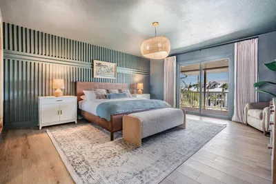 Luxurious bedroom with a king bed, elegant lighting, and soft coastal hues. Sliding doors open to a private balcony with serene water views, creating a relaxing retreat that perfectly blends comfort and sophistication.