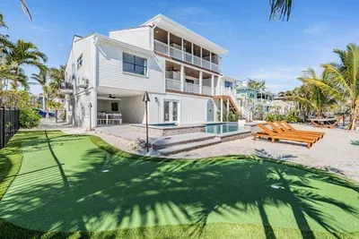 Tropical paradise with a sparkling pool, putting green, and sun loungers surrounded by palm trees. This coastal retreat blends outdoor fun with modern comfort—perfect for relaxing poolside, entertaining, or enjoying warm evenings under the stars.