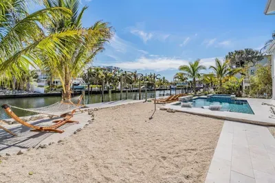 Private sandy oasis with hammocks, palm trees, and a sparkling canal-front pool. This tropical retreat invites you to unwind under the sun, enjoy tranquil water views, and embrace pure island-style relaxation.