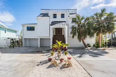 Modern coastal home with striking architecture, tropical landscaping, and grand entryway. Offering ample parking and island charm, this stunning retreat sets the tone for a luxurious waterfront getaway from the moment you arrive.