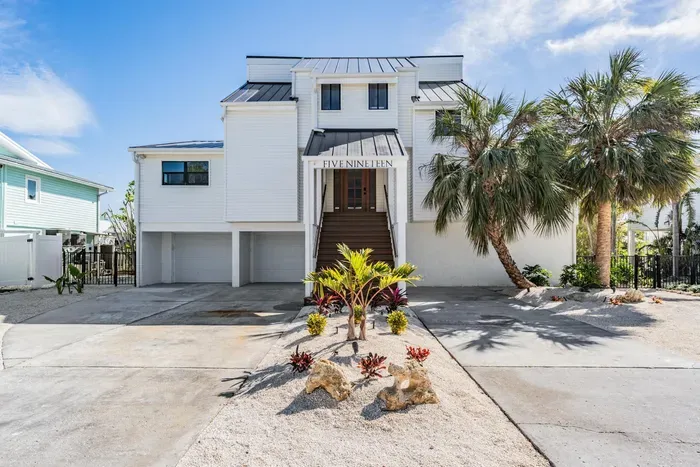 Modern coastal home with striking architecture, tropical landscaping, and grand entryway. Offering ample parking and island charm, this stunning retreat sets the tone for a luxurious waterfront getaway from the moment you arrive.