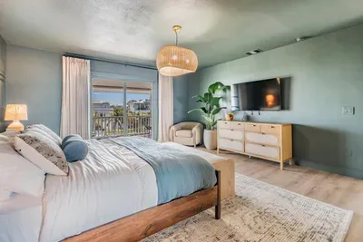Elegant bedroom retreat with soft ocean hues, a plush king bed, and a private balcony overlooking the water. Featuring modern décor and a cozy seating nook, this serene space invites total relaxation and comfort.