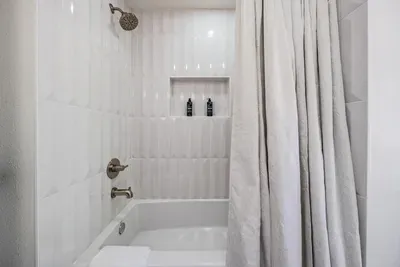 Bright and modern shower-tub combo with elegant white tile and brushed nickel fixtures. Clean, simple, and refreshing—perfect for a relaxing rinse after a day by the beach or pool.