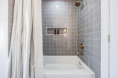 Chic shower-tub combo with sleek gray tile and gold fixtures. Modern and inviting, this space offers a perfect blend of style and comfort for a refreshing coastal-inspired bath experience.