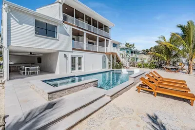 Stunning waterfront retreat featuring a sparkling pool, spa, and sun loungers surrounded by tropical landscaping. With multiple balconies and shaded dining areas, it’s the ultimate blend of luxury, comfort, and coastal living.