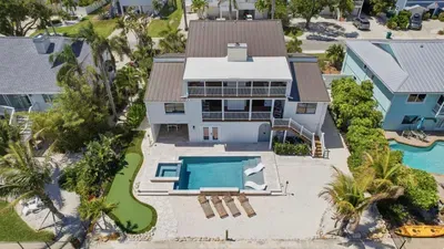 Stunning waterfront escape featuring a private dock, sparkling pool, and multiple balconies with breathtaking sunset views.