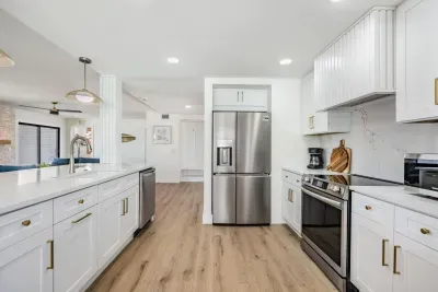 Sleek and airy kitchen featuring stainless steel appliances, white cabinetry, and quartz countertops. The open design and modern finishes make it perfect for cooking, entertaining, or simply enjoying coffee with a view of the bright living area.