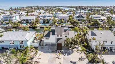 Aerial view of a stunning canal-front home surrounded by luxury coastal estates. With direct water access, tropical landscaping, and a sleek modern design, this getaway offers the perfect blend of privacy, beauty, and island living.