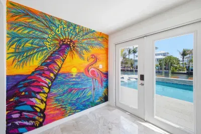 Vibrant tropical mural brings bold color and energy to this bright space, paired with glass doors leading to the pool. Enjoy seamless indoor-outdoor living with stunning water views and a lively, artistic coastal vibe.