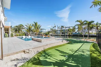 Tropical backyard paradise featuring a sparkling pool, spa, and private putting green. Overlooking a peaceful canal, this vibrant outdoor space is perfect for relaxing, entertaining, or enjoying fun in the Florida sun.