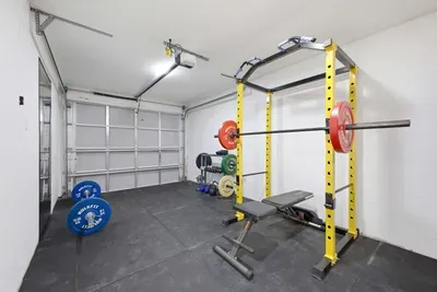 Private garage gym setup with power rack, bench, and free weights—perfect for staying active during your stay. Clean, spacious, and well-lit with durable flooring, it’s ideal for strength training or quick workouts just steps away.