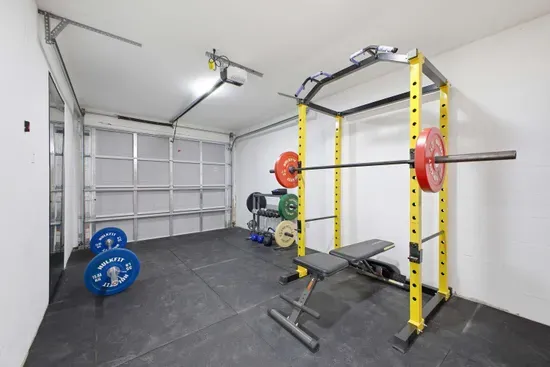 Private garage gym setup with power rack, bench, and free weights—perfect for staying active during your stay. Clean, spacious, and well-lit with durable flooring, it’s ideal for strength training or quick workouts just steps away.
