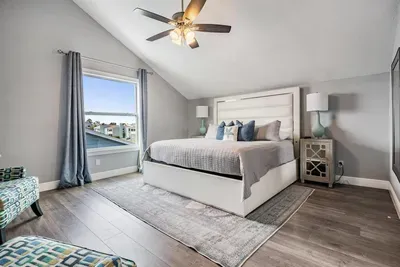 Relax in the elegant master suite featuring a plush king bed, vaulted ceilings, chic décor, and large windows with serene water views. Perfect for unwinding in comfort and style after a day of adventure.