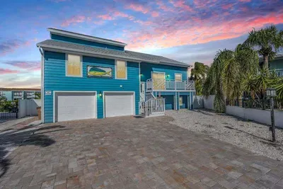 Coastal charm meets modern elegance! This vibrant blue retreat boasts a spacious driveway, balconies, and tropical landscaping. The perfect first impression, inviting you into a luxurious waterfront getaway.