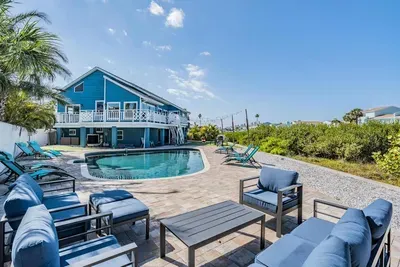 Stunning outdoor oasis with a sparkling pool, lounge chairs, and cozy seating areas. Perfect for sunbathing, relaxing, or entertaining while surrounded by lush greenery and coastal charm. Your private paradise awaits!