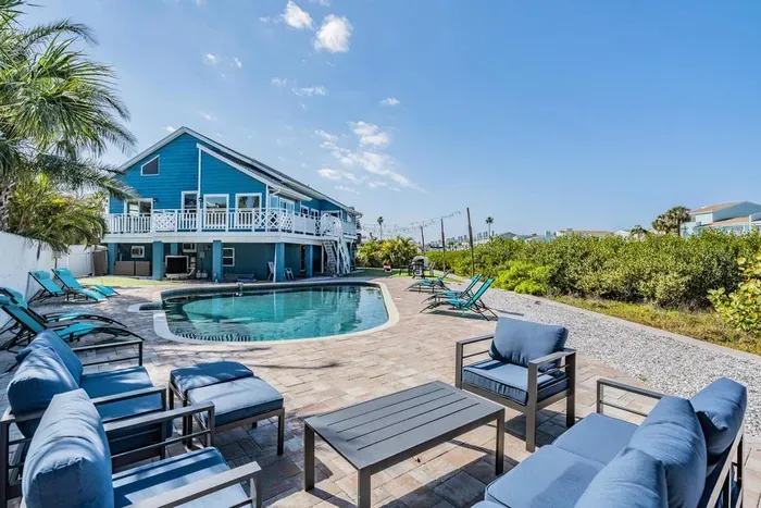 Stunning outdoor oasis with a sparkling pool, lounge chairs, and cozy seating areas. Perfect for sunbathing, relaxing, or entertaining while surrounded by lush greenery and coastal charm. Your private paradise awaits!