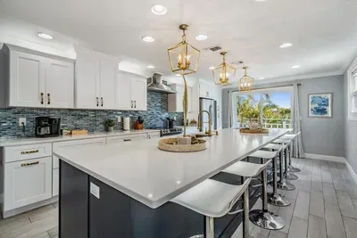This gourmet kitchen boasts a massive quartz island with seating for 8, sleek cabinetry, stainless steel appliances & designer lighting. Bright, open, and perfect for cooking, dining & gathering with family and friends.