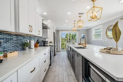 Stunning gourmet kitchen featuring quartz countertops, designer lighting, sleek cabinetry & stainless steel appliances. Spacious island with seating makes it perfect for cooking, entertaining, & creating unforgettable meals together.