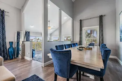 Elegant dining space featuring a sleek wooden table, plush navy chairs, and modern accents. Surrounded by windows, this bright and stylish area is perfect for family dinners, holiday feasts, or intimate gatherings.