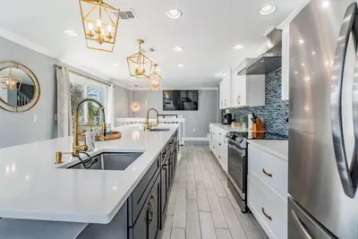 Sleek quartz counters, custom cabinetry, stainless steel appliances & designer lighting create a modern, elegant space. Perfect for cooking, entertaining & gathering in style.