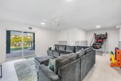 This spacious game room features plush sectional seating, arcade fun, and direct access to the outdoors. Perfect for family game nights, kids’ playtime, or simply relaxing in a lively, entertainment-filled space.