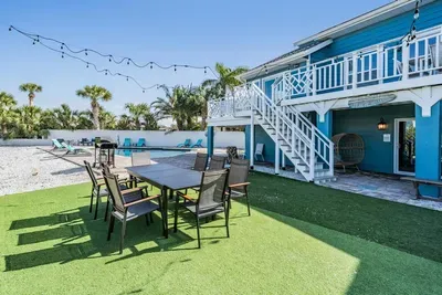 Gather under string lights at the spacious table, steps from the pool and lush yard. Perfect for family meals, sunset dinners, or evening cocktails in a relaxed coastal setting.