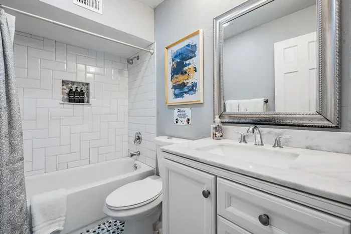 Bathroom 2 offers convenience and style with a sleek vanity, bright lighting, and a tub/shower combo surrounded by modern tile. A shared space designed for comfort, making it perfect for families or groups.