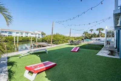 Outdoor fun meets waterfront living! Enjoy a private yard with turf, string lights, lounging areas & games—perfect for entertaining or relaxing by the water. Create unforgettable memories in this vibrant retreat!