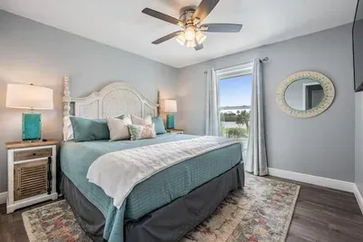 Bedroom 3 features a luxurious king bed, coastal-inspired décor, and bright natural light. With calming tones and chic accents, this space is designed for both comfort and style—ideal for restful nights and peaceful mornings.