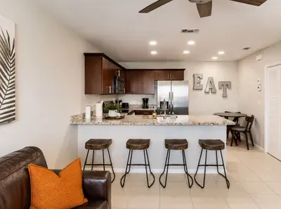 Bright, open kitchen with granite countertops, stainless-steel appliances, and warm wood cabinetry. Perfect for cooking or gathering at the chic breakfast bar with industrial stools. A cozy, inviting space that blends modern style with comfort.