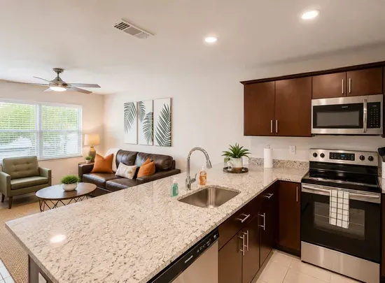 Modern kitchen with sleek granite counters, stainless-steel appliances, and rich wood cabinetry overlooking a bright, cozy living space. Perfect for cooking, entertaining, or relaxing in comfort and style.