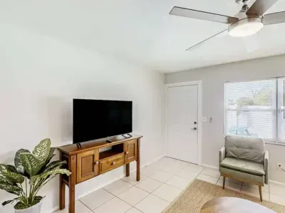 Cozy entertainment space with a flat-screen TV, stylish wood console, and comfy armchair. Bright natural light and modern touches create the perfect spot to unwind and enjoy your favorite shows after a day of exploring.