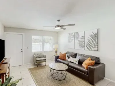 Bright and inviting living room featuring a sleek leather sofa, modern décor, and natural light streaming through large windows. Perfect for relaxing after a day of adventure, blending comfort and contemporary coastal charm.