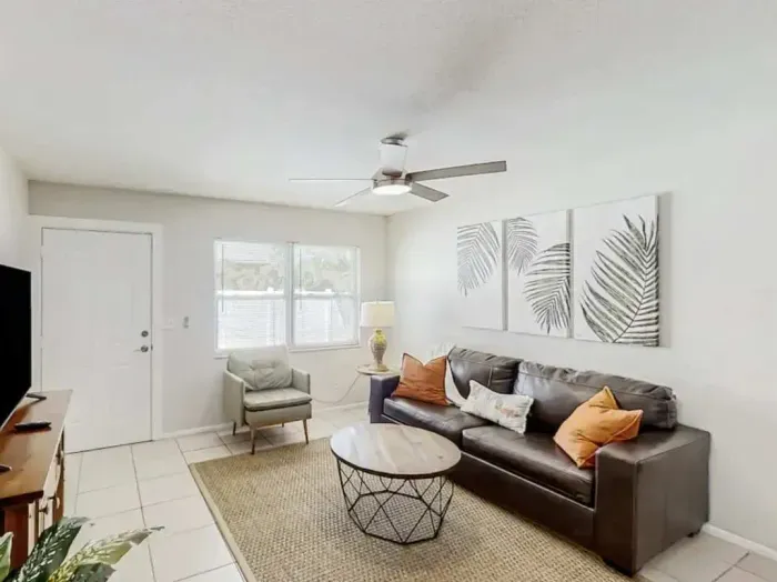 Bright and inviting living room featuring a sleek leather sofa, modern décor, and natural light streaming through large windows. Perfect for relaxing after a day of adventure, blending comfort and contemporary coastal charm.