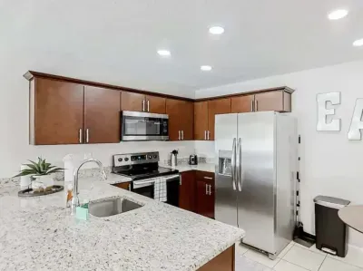 Sleek modern kitchen featuring stainless-steel appliances, granite countertops, and rich wood cabinetry. Fully equipped for cooking and entertaining, this bright space blends functionality with contemporary charm.