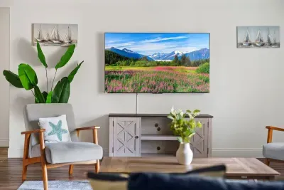 Stylish and cozy living area featuring a large flat-screen TV, modern décor, and comfortable seating.