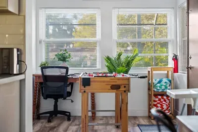 Sunny, multi-use bonus room with a fun foosball table and a dedicated desk for remote work! Large windows bring in beautiful natural light, creating a bright and cheerful space for game nights, productivity, or relaxing between pool days.