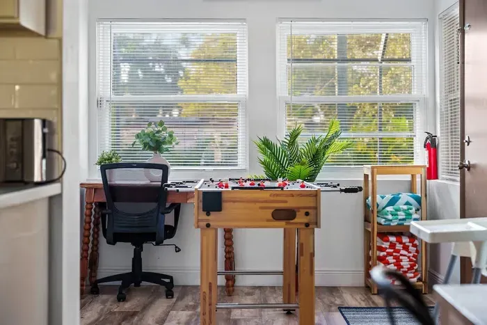 Sunny, multi-use bonus room with a fun foosball table and a dedicated desk for remote work! Large windows bring in beautiful natural light, creating a bright and cheerful space for game nights, productivity, or relaxing between pool days.