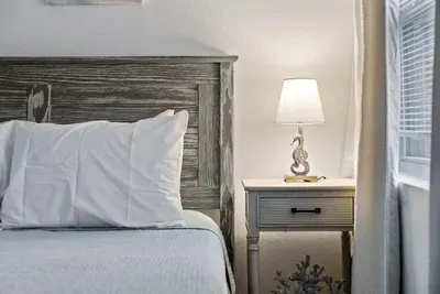Cozy queen bedroom details that make you feel right at home! Enjoy a comfortable bed with fresh linens, charming coastal-style furniture, and soft bedside lighting. Perfect for winding down and relaxing in a calm, inviting space.