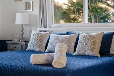 Sink into this cozy king bed dressed in fresh linens and plush pillows, with soft natural light and peaceful views just outside the window. A calm, comfortable space designed for deep rest—perfect after a day of pool time.