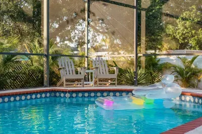 Soak up the sunshine in your private screened-in pool oasis! Sparkling water, brick-trimmed deck, tropical landscaping, and comfy lounge seating create the perfect retreat.