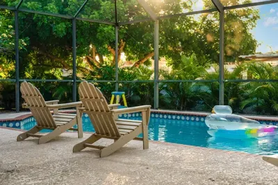 Relax poolside in this private screened-in retreat! Enjoy comfortable lounge chairs, sparkling water, and lush tropical landscaping that creates a peaceful, resort-style atmosphere.