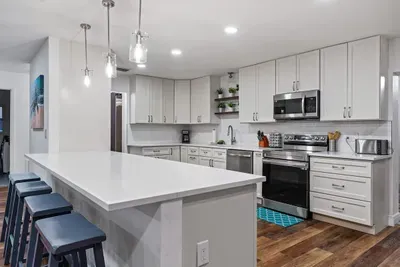 Sleek, modern kitchen designed for cooking and gathering! Featuring crisp white cabinetry, stainless steel appliances, stylish pendant lighting, and a spacious island with seating. Bright, open, and beautifully finished.