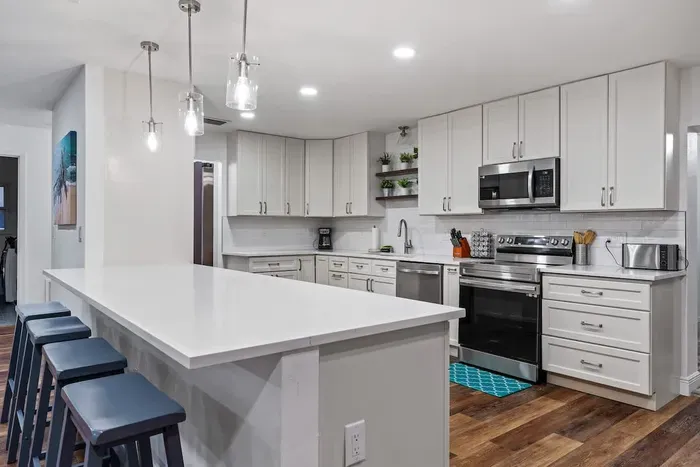 Sleek, modern kitchen designed for cooking and gathering! Featuring crisp white cabinetry, stainless steel appliances, stylish pendant lighting, and a spacious island with seating. Bright, open, and beautifully finished.