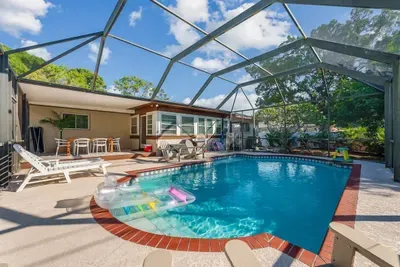 Resort-style screened pool oasis perfect for sunny Florida days! Enjoy sparkling turquoise water, a spacious brick-trimmed deck, lounge chairs, and a covered patio for outdoor dining. Private and ideal for entertaining or family fun year-round.
