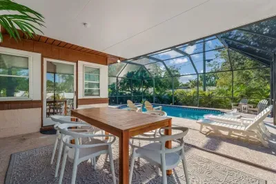 Dine and unwind in this gorgeous screened lanai overlooking a sparkling pool! Enjoy a spacious outdoor table, lounge chairs for sunbathing, and peaceful tropical views.